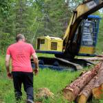 Walt Blauvelt walks toward a pile of logs near the Central Peninsula Landfill on Thursday, July 1, 2021 near Soldotna, Alaska. (Ashlyn OHara/Peninsula Clarion)