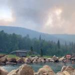 In this photo provided by the Alaska Division of Forestry, smoke from the Munson Creek Fire rises behind the Chena Hot Springs Resort as guests watch from the outdoor rock pool near Fairbanks, Alaska, on Monday, July 5, 2021. Authorities on Monday advised residents and guests at an Alaska hot springs resort to evacuate immediately after a nearby wildfire intensified. The Fairbanks North Star Borough issued the evacuation order when the fire reached a point less than a mile behind Chena Hot Springs. (Alaska Division of Forestry via AP)