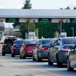 A line of vehicles wait to enter Canada at the Peace Arch border crossing Monday, Aug. 9, 2021, in Blaine, Wash. Canada lifted its prohibition on Americans crossing the border to shop, vacation or visit, but America kept similar restrictions in place, part of a bumpy return to normalcy from coronavirus travel bans. (AP Photo/Elaine Thompson)