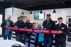 Homer Truffle Co. owner David Briggs cuts the grand opening ribbon at the relaunch of his business on Aug. 17. He is pictured with Homer Chamber of Commerce and Visitor Center board members and employees. (Photo by Sarah Knapp/Homer News)