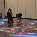 Artists work to stage a new mural that will be installed later this week  or when the rain lets up and the weather allows work to proceed outside. (Dana Zigmund/Juneau Empire)