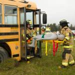 Firefighters carry a plane crash victim on a stretcher from the crash site. As a part of the drill, the patient was then transported to a local medical facility. (Photo by Sarah Knapp/Homer News)