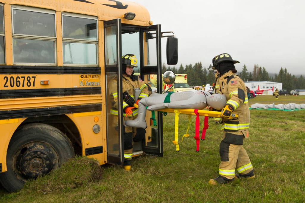 Firefighters carry a plane crash victim on a stretcher from the crash site. As a part of the drill, the patient was then transported to a local medical facility. (Photo by Sarah Knapp/Homer News)