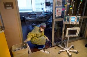 An ICU nurse, moves electrical cords for medical machines, outside the room of a patient suffering from COVID-19, in an intensive care unit at the Willis-Knighton Medical Center in Shreveport, La. The COVID-19 pandemic has created a nurse staffing crisis that is forcing many U.S. hospitals to pay top dollar to get the help they need to handle the crush of patients this summer. (AP Photo/  Gerald Herbert)