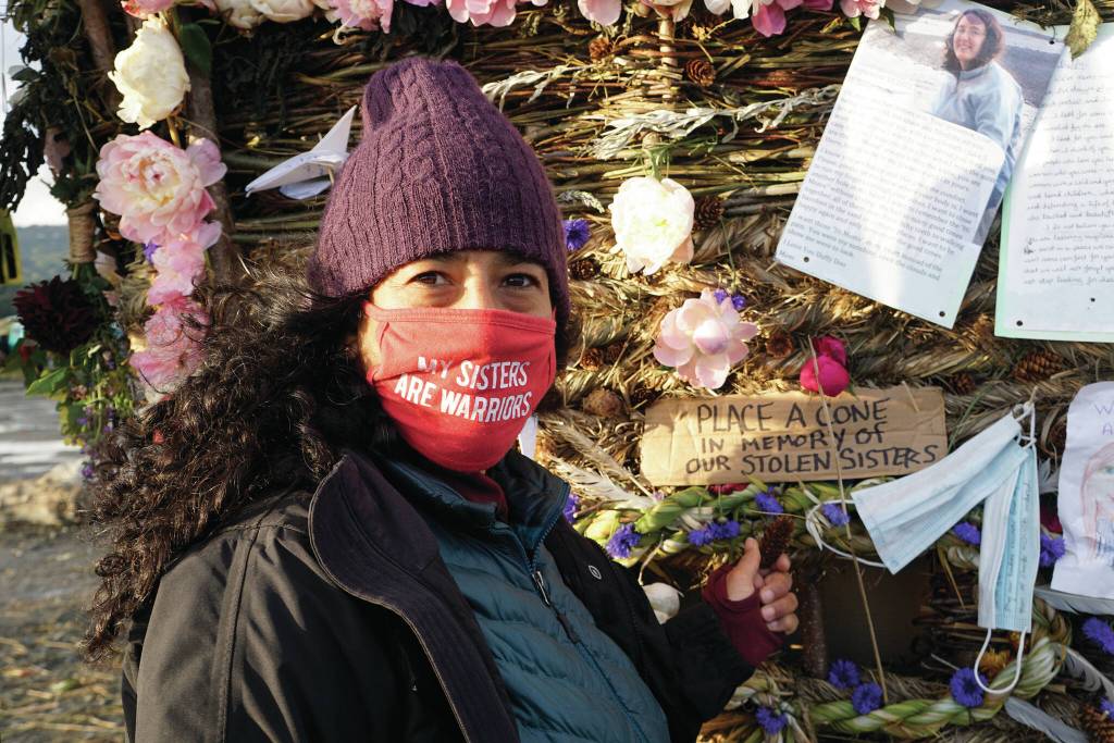 Elizabeth Lakschmi Kanter places a cone in memory of missing and endangered women into Recover, the 18th annual Burning Basket, on Sunday, Sept. 12, 2021, at Mariner Park on the Homer Spit in Homer, Alaska. A photo above is of Anesha Duffy Murnane, a Homer woman missing since October 2019. (Photo by Michael Armstrong/Homer News)