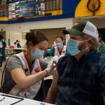 Anna Lewald, left, a registered nurse at South Peninsula Hospital, gives Dave Aplin, right, an influenza vaccine at a flu and Pfizer COVID-19 vaccine clinic Friday, Oct. 15, 2021, at Homer High School in Homer, Alaska. (Photo by Michael Armstrong/Homer News)