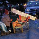 Aaron Fleenor, at top, uses a chute to distribute candy on Halloween night, Oct. 31, 2020, in downtown Homer, Alaska. Helping are Amber Fleenor, center, and Shade Fleenor, left. Because of COVID-19 safety concerns, some people created devices like this to give candy away while keeping social distance. Trick or treating was more subdued than usual, but still drew children in costume to neighborhood above Pioneer Avenue. (Photo by Michael Armstrong/Homer News)