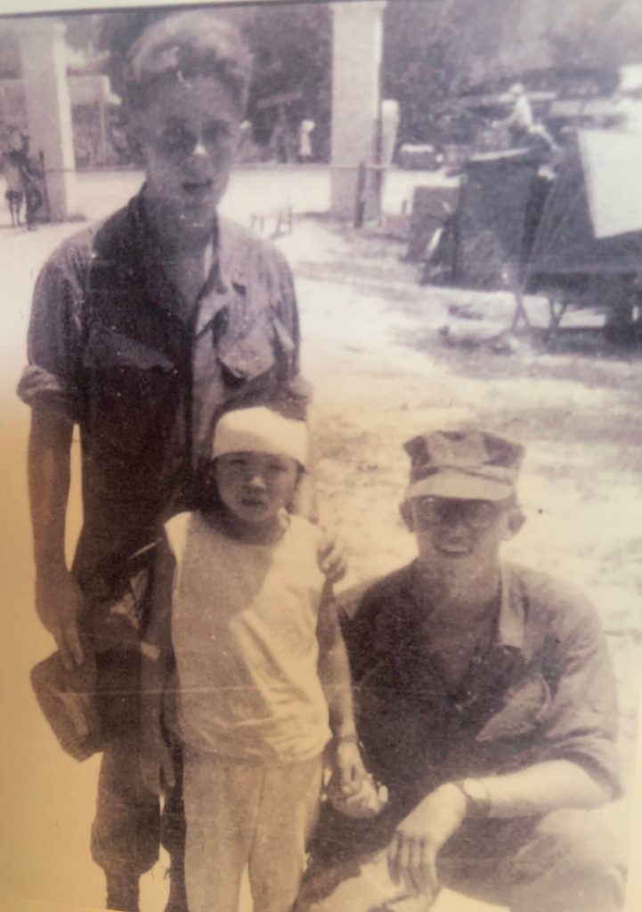 Cpl. Gary Squires kneels next to a young Vietnamese girl he helped rescue and the doctor who bandaged her wounds. (Photo provided by Gary Squires)