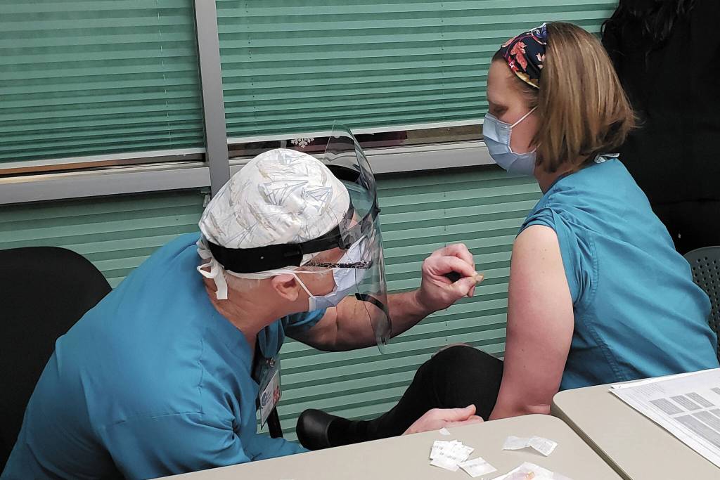 Family practice physician Christina Tuomi, D.O., (right) gets Homers first dose of Pfizers COVID-19 vaccine from Emergency Department nurse Steve Hughes (left) on Thursday, Dec. 17, 2020 at South Peninsula Hospital in Homer, Alaska. Tuomi has been the hospitals medical lead throughout the pandemic. (Photo courtesy Derotha Ferraro/South Peninsula Hospital)
