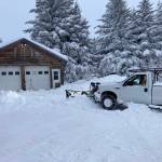 Jim Levine, left, watches as his Diamond Ridge driveway gets plowed on Monday, Nov. 29, 2021, near Homer, Alaska. Over the Thanksgiving Day weekend, some areas of the southern Kenai Peninsula got up to 3 feet of snow. The weekend forecast calls for clear and cold on Friday, with a 70% chance of snow on Sunday, (Photo by Michael Armstrong/Homer News)