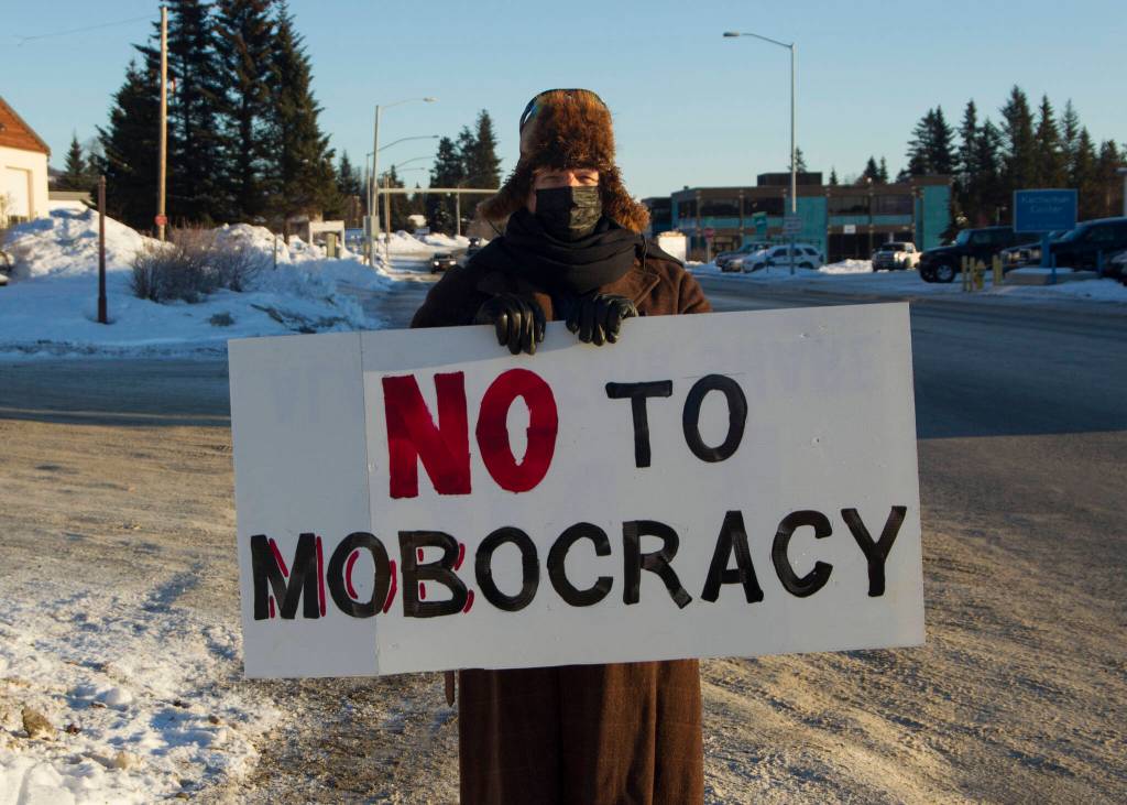 A man shows his sign, which states No to Mobocracy, to passing cars in opposition of the Jan. 6 insurrection at the U.S. Capitol. (Photo by Sarah Knapp/Homer News)