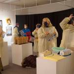 Visitors put on personal protective equipment before an artist talk by Dr. Sami Ali' at the Jan. 7, 2022, First Friday opening of her exhibit, "The Mind of a Healthcare Worker During the COVID-19 Pandemic," at the Homer Council on the Arts in Homer, Alaska. (Photo by Michael Armstrong/Homer News)
