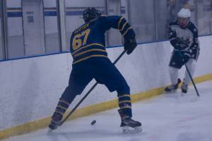 Matfey Reutov moves the puck down the rink against a Soldotna High School player on Friday, Jan. 14. (Photo by Sarah Knapp/Homer News)