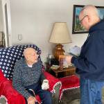 Matt Haney reads Toras Fisk the return address labels on a new stack of birthday cards he received just days before his 100th birthday. Haney is Fisks caretaker. (Photo by Sarah Knapp/Homer News)