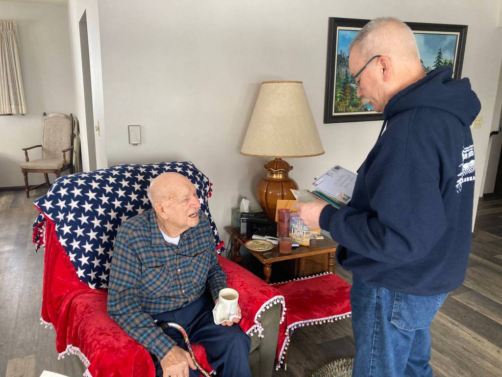 Matt Haney reads Toras Fisk the return address labels on a new stack of birthday cards he received just days before his 100th birthday. Haney is Fisks caretaker. (Photo by Sarah Knapp/Homer News)