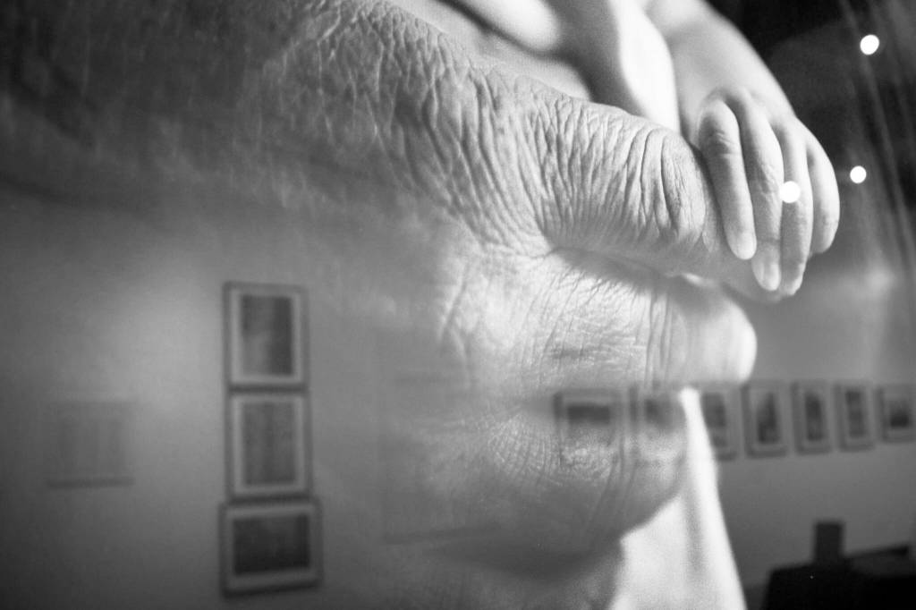 Lisa Williams photography exhibit is reflected in the glass of a print for her photo, Nick Tanape Sr. and grandson, as seen at the Pratt Museum & Park on Feb. 28, 2022, in Homer, Alaska. (Photo by Sean McDermott)
