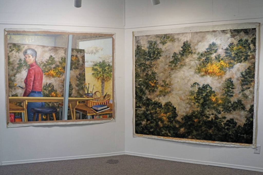 Photo by Michael Armstrong/Homer News 
Selected Works and Sketches by Gaye Wolfe, showing at the Homer Council on the Arts through March, includes these two paintings by Wolfe: a painting of a wildfire, right, and then a self-portrait of Wolfe, left, creating the painting.