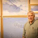 David Rosenthal poses for a portrait in front of paintings from his time in Antarctica at the Pratt Museum & Park in Homer, Alaska. (Photo by Sean McDermott)