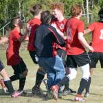 The Kenai Central boys soccer teams mobs Joe Hamilton (center) after Hamilton scored the game-winning penalty kick in the Peninsula Conference championship game Saturday, May 21, 2022, at Nikiski High School in Nikiski, Alaska. (Photo by Jeff Helminiak/Peninsula Clarion)