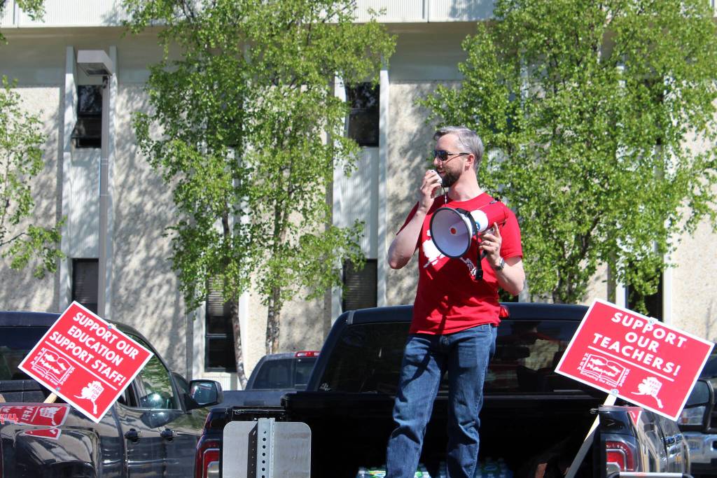 Kenai Peninsula Education Association President Nathan Erfurth speaks from the bed of his truck in support of Kenai Peninsula Borough School District teachers and support staff outside of the George A. Navarre Admin Building on Thursday, May 26, 2022 in Soldotna, Alaska. (Ashlyn OHara/Peninsula Clarion)