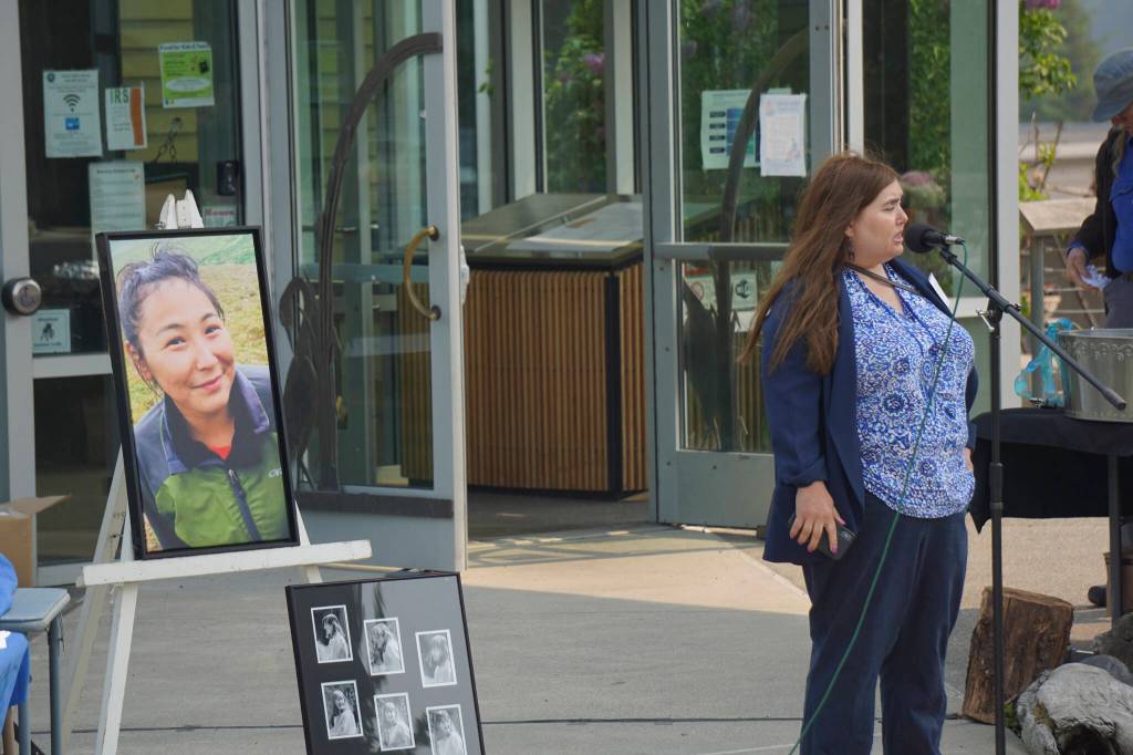Ingrid Cumberlidge, the Missing and Murdered Indigenous Persons coordinator for the U.S. Attorneys office in Alaska, speaks at the memorial for Anesha Duffy Murnane and the dedication of the Loved & Lost Memorial Bench on Sunday, June 12, 2022, at the Homer Public Library in Homer, Alaska. At left is a photo of Florence Okpealuk, who went missing from the Nome beach on Aug. 31, 2020. (Photo by Michael Armstrong/Homer News)