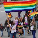 People holding a Pride banner lead the Pride-X-Juneteenth parade on Saturday, June 18, 2022, on Pioneer Avenue in Homer, Alaska. (Photo by Michael Armstrong/Homer News)