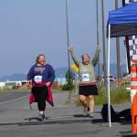 Walkers Jenny Johnson, left, and Jane Nollar, right, cross the finish line in the 2022 Homer Spit Run on Saturday, June 25, 2022, at the End of the Road Park in Homer, Alaska. (Photo by Michael Armstrong/Homer News)