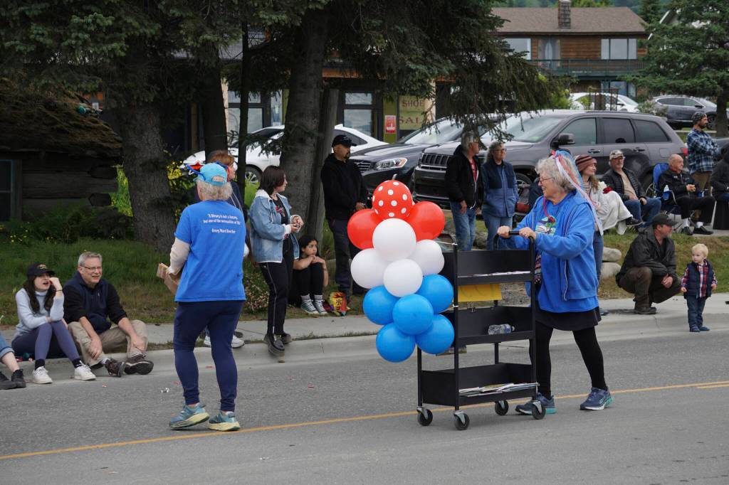 Sara Reinert, right, pushes a book cart with the Friends of the Homer Public Library group during the Homer Fourth of July parade on Monday, July 4, 2022, on Pioneer Avenue in Homer, Alaska. (Photo by Michael Armstrong/Homer News)