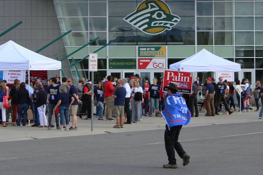 A man wearing a Trump flag crosses the street in front of the Alaska Airlines Center, where a Save America rally was being held, on Saturday, July 9, 2022 in Anchorage, Alaska. Former President Donald Trump, U.S. Senate candidate Kelly Tshibaka and U.S. House candidate Sarah Palin were among the events speakers. (Ashlyn OHara/Peninsula Clarion)