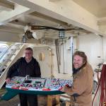 Center for Alaskan Coastal Studies CoastWalk Coordinator Henry Reiske, right, and Alaska Maritime National Wildlife Refuge Manager Steve Delehanty, left, carry the R/V APAK onto the R/V Tiglax on Friday, July 15, 2022, in Homer, Alaska. (Photo by Charlie Menke)