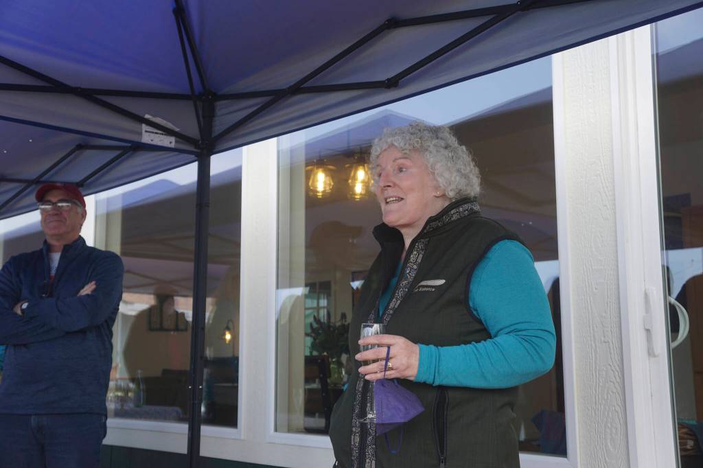 Storyknife Writers Retreat founder and writer Dana Stabenow speaks on the deck of Eva, the main cabin of the complex, at an open house on Monday, Aug. 29, 2022, at the retreat near Homer, Alaska. At left is Dave Girard, one of the carpenters who worked on the project and built the custom dining table for Eva, named after poet Eva Saulitis. (Photo by Michael Armstrong/Homer News)