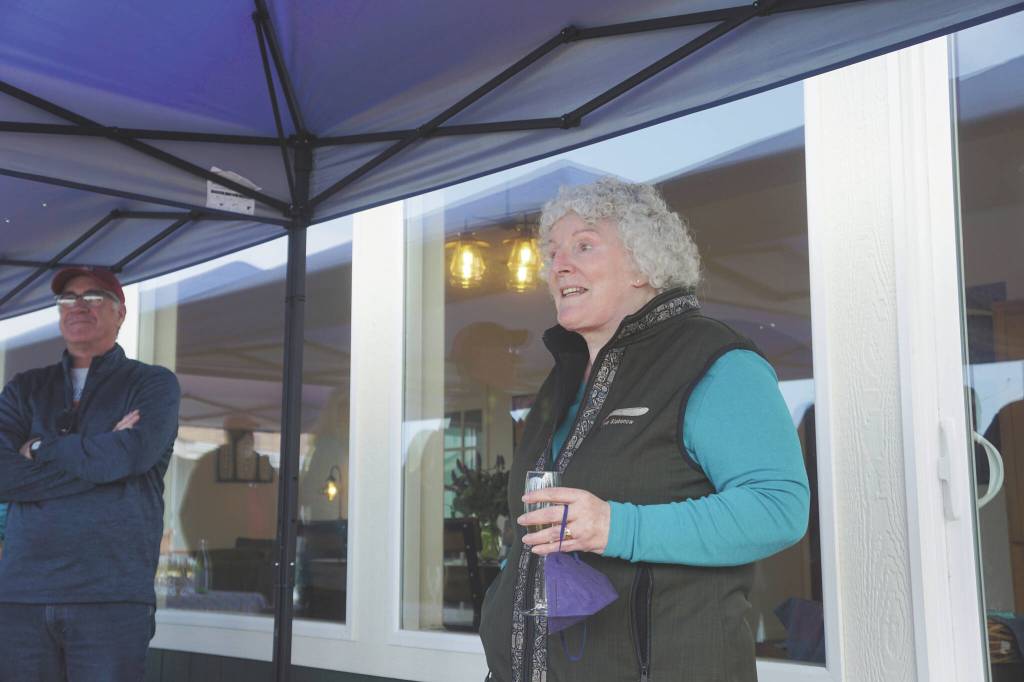 Storyknife Writers Retreat founder and writer Dana Stabenow speaks on the deck of Eva, the main cabin of the complex, at an open house on Monday, Aug. 29, at the retreat near Homer. At left is Dave Girard, one of the carpenters who worked on the project and built the custom dining table for Eva.