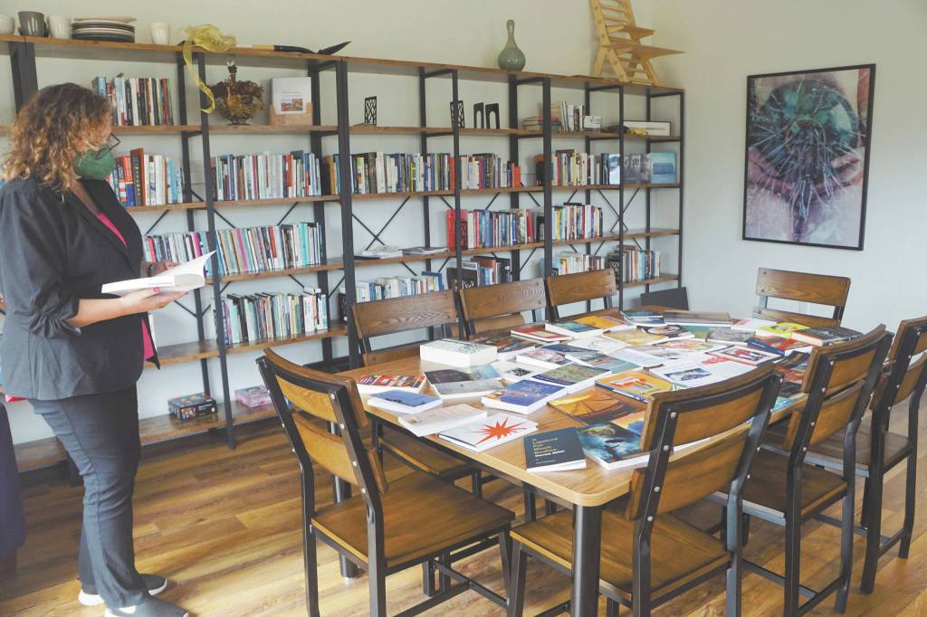 At an open house for the Storyknife Writers Retreat on Monday, Aug. 29, Storyknife board member Patty Stith looks at one of the books published by past Storyknife fellows in the library of Eva, the main house for the retreat near Homer.