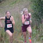 Emilee Wilson, left, of Kenai duels with Megan Nelson, right, of Grace Christian on the last hill of the Homer Invite on Friday, Sept. 2, 2022, at the Lookout Mountain Trails near Homer, Alaska. Nelson took fourth by just 4.23 seconds. (Photo by Michael Armstrong/Homer News)