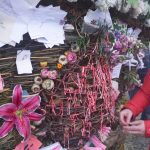 A woman ties a red ribbon on the Sphere of Love, a memorial small basket for Anesha Duffy Murnane placed on the 19th annual Burning Basket, Breathe, on Sunday, Sept. 11, 2022, at Mariner Park on the Homer Spit. People were asked to take three spruce cones, think positive thoughts, and put them in the Sphere of Love. Ribbons tied on the basket honored missing and murdered people. Murnanes family donated envelopes from cards of remembrance sent to them, and the cards were folded into fans on the basket. (Photo by Michael Armstrong/Homer News)