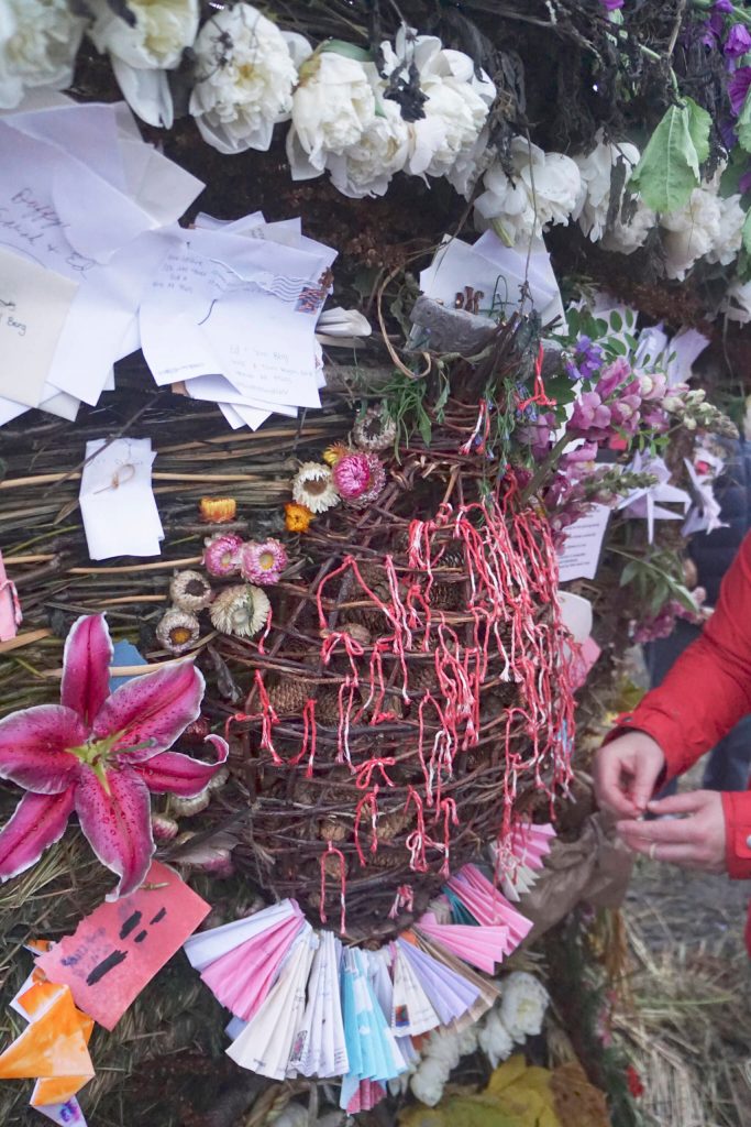 A woman ties a red ribbon on the Sphere of Love, a memorial small basket for Anesha Duffy Murnane placed on the 19th annual Burning Basket, Breathe, on Sunday, Sept. 11, 2022, at Mariner Park on the Homer Spit. People were asked to take three spruce cones, think positive thoughts, and put them in the Sphere of Love. Ribbons tied on the basket honored missing and murdered people. Murnanes family donated envelopes from cards of remembrance sent to them, and the cards were folded into fans on the basket. (Photo by Michael Armstrong/Homer News)