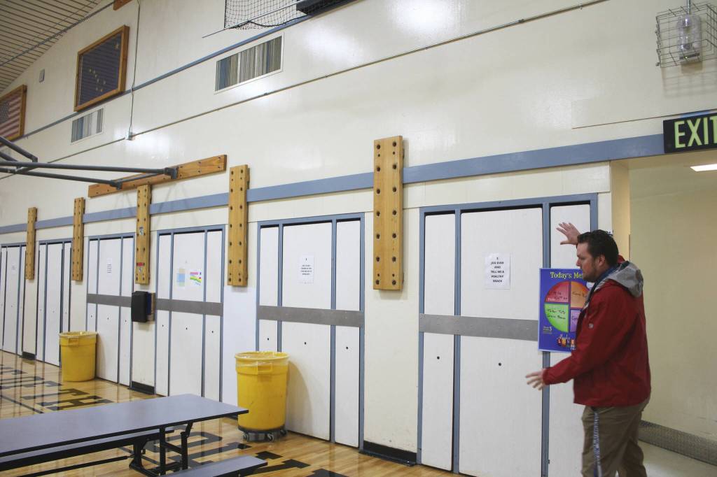 Soldotna Elementary School Principal Dr. Austin Stevenson gestures to lunch tables that are nailed into the gym wall on Friday, Sept. 30, 2022, in Soldotna, Alaska. (Ashlyn OHara/Peninsula Clarion)