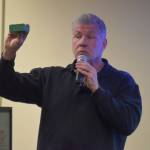 Patrick Simpson speaks about his recycled plastic lumber project while holding a sample of the finished product at a Kenai Peninsula College Showcase on Thursday, Oct. 27, 2022 in Soldotna, Alaska. (Jake Dye/Peninsula Clarion)