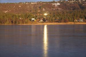 Sun reflected in windows on a house shines on the ice of Beluga Lake on Monday, Nov. 14, 2022, in Homer, Alaska. (Photo by Michael Armstrong/Homer News)