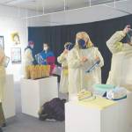 Photo by Michael Armstrong/Homer News 
Visitors put on personal protective equipment before an artist talk by Dr. Sami Ali at the Jan. 7 First Friday opening of her exhibit, The Mind of a Healthcare Worker During the COVID-19 Pandemic, at the Homer Council on the Arts.