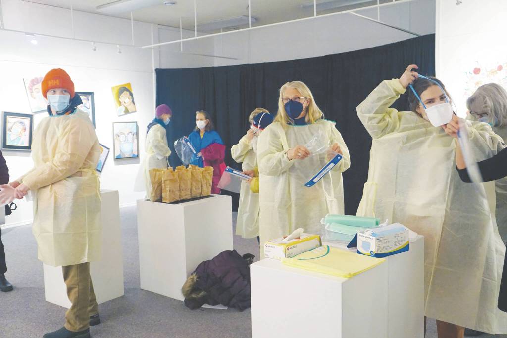 Photo by Michael Armstrong/Homer News 
Visitors put on personal protective equipment before an artist talk by Dr. Sami Ali at the Jan. 7 First Friday opening of her exhibit, The Mind of a Healthcare Worker During the COVID-19 Pandemic, at the Homer Council on the Arts.