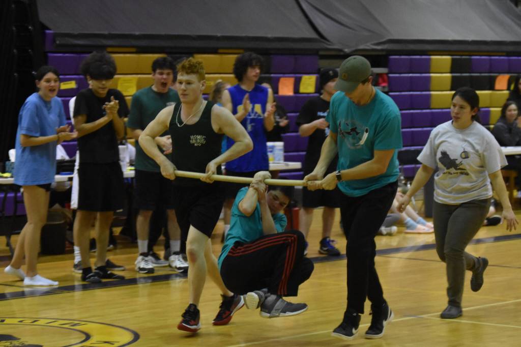 Dakota Butler hangs from a wooden pole by only his wrist as he performs the wrist carry during the Kahtnuhtana Hey Chiula NYO Invitational on Saturday, Jan. 14, 2023, at Kenai Middle School in Kenai, Alaska. Butler held on for more than 200 feet, claiming the gold medal in the event. (Jake Dye/Peninsula Clarion)