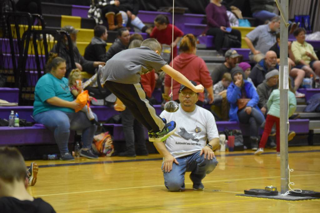 A junior athlete competing for the Kenaitze Indian Tribe performs the two-foot high kick during the Kahtnuhtana Hey Chiula NYO Invitational on Saturday, Jan. 14, 2023, at Kenai Middle School in Kenai, Alaska. (Jake Dye/Peninsula Clarion)