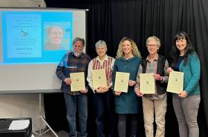 (from left to right) HCOA Community Arts awardees Daniel Perry (on screen), Michael Armstrong, Cathy Stingley, Krista Etzweiler, Sherry Stead and Brianna Allen pose with their awards at the HCOA annual meeting on Jan. 27, 2023, in Homer, Alaska.