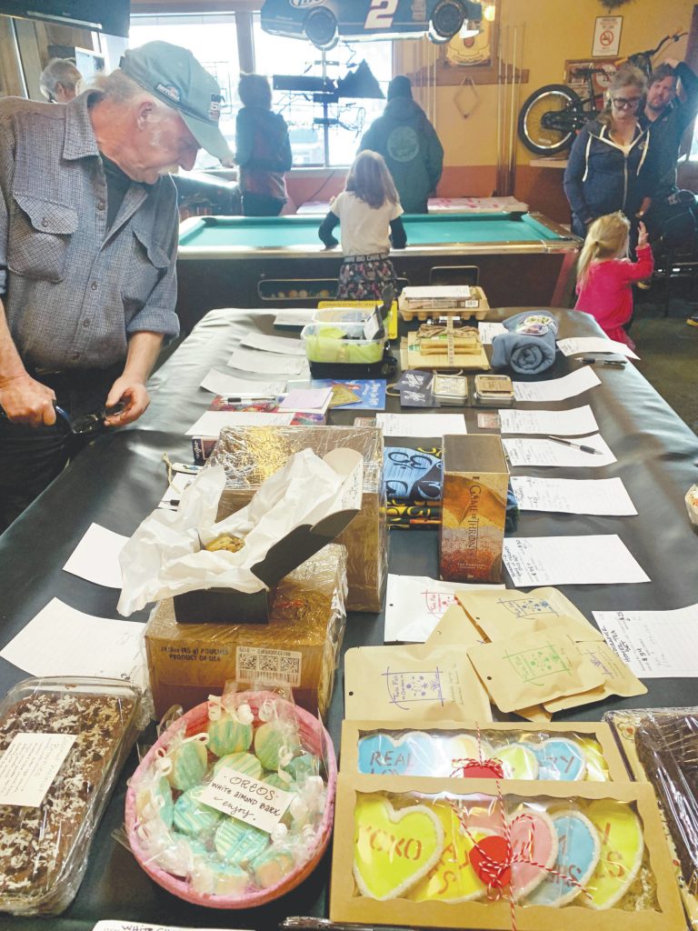 A community member checks out items in the silent auction, part of a benefit held last Saturday at the Down East Saloon for the Pariyar Family that raised more than $5,000. (Photo by Christina Whiting/Homer News)