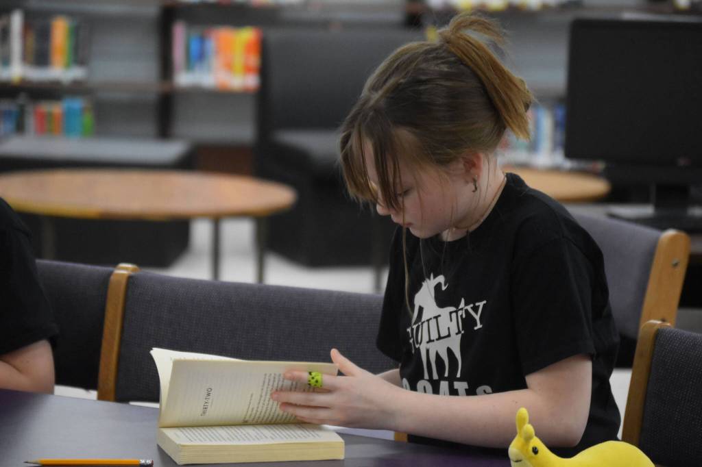 Arianna Imlay searches Girl in the Blue Coat by Monica Hesse for evidence to support a challenge issued during Kenai Peninsula Borough School District Middle School Battle of the Books competition on Thursday, Feb. 9, 2023, at Kenai Middle School in Kenai, Alaska. The challenge would ultimately be declared successful. (Jake Dye/Peninsula Clarion)