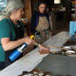 Ann-Margaret Wimmerstedt heats a plywood board for painting with encaustics on July 20, 2018 at Wimmerstedts home as artist Carla Klinker-Cope watches.