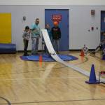Pinewood derby contestants Simon Smith, Rox Shafer, and Jack Roderick and event volunteer Mike Smith watch the cars race down the track in the Chapman School gym on Saturday<ins>,</ins><ins> March 4</ins> in Anchor Point<ins>,</ins> <ins>Alaska</ins>. (Photo by Delcenia Cosman/Homer News)
