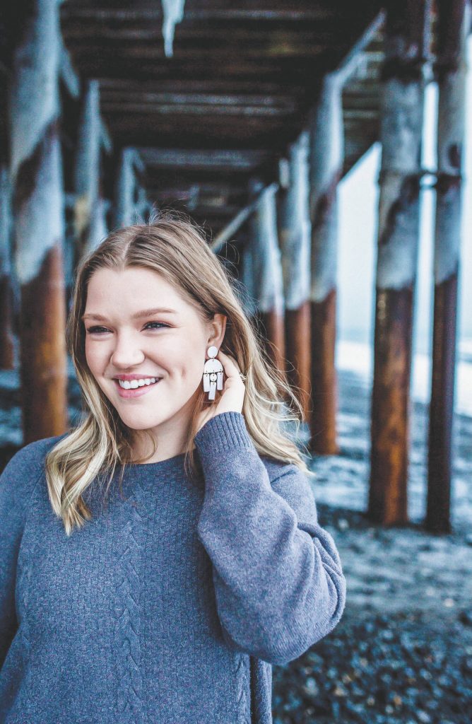 Alyssa Morgan on the Homer Spit wearing a pair of her polymer clay earrings, December 2021. (Photo by Goldie Shealy, Gold Portrait Co.)