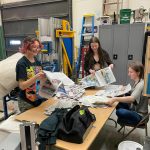 Newsies crew Vern Neveras, Bryce Glidden and Jasmine Lurus in the Homer Mariner Theater shop on March 5 preparing newspaper props for the musical.  Photo by Emilie Springer.